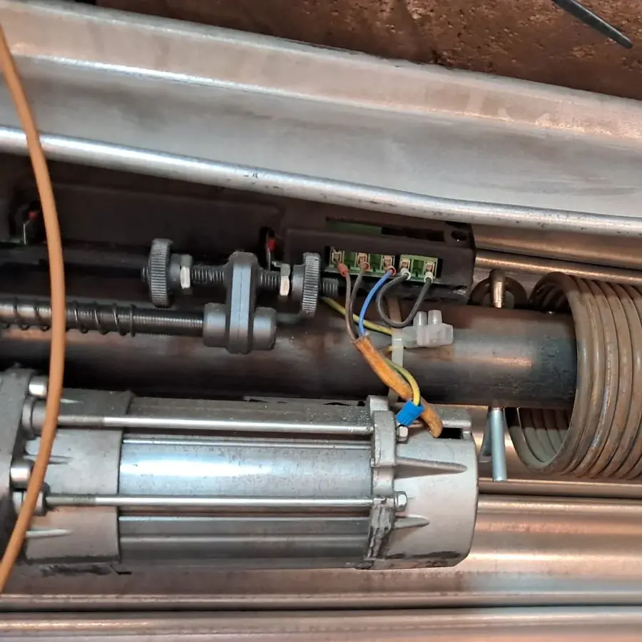 Interior del cajón de una persiana: motor tubular abierto con los finales de carrera y el cableado a la vista